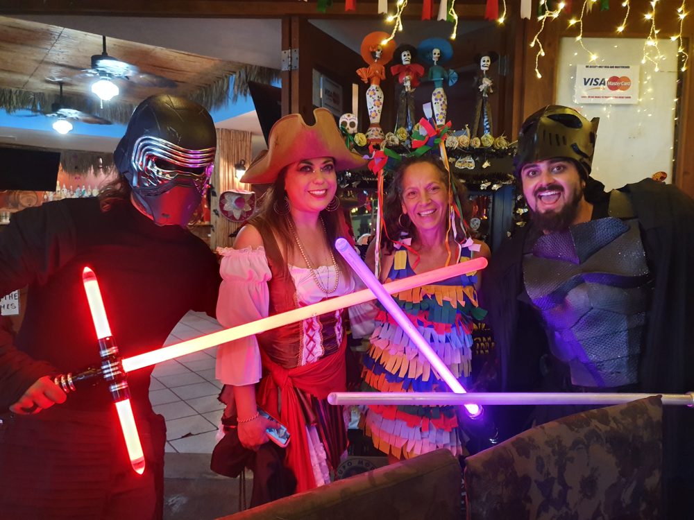 Cabo Cantina customers in Halloween costumes posing with colorful lightsabers.